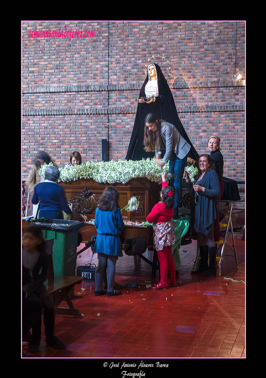 En la mañana del Lunes Santo mujeres y niños se afanan en colocar las flores del paso de Nuestra Señora de Amor y Sacrificio