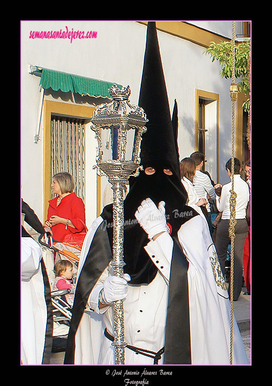 Nazareno con cirial de respeto acompañando al Simpecado de la Hermandad de la Coronación de Espinas