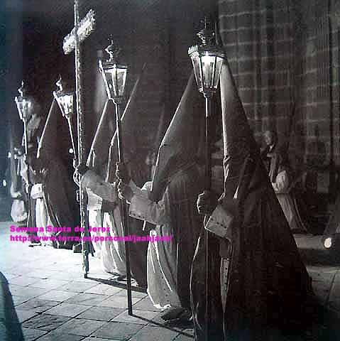 Año 1954. La Hermandad de la Cena haciendo estación la Colegial. Era su primera estación de penitencia. En 1963 cambió su salida del Jueves al Martes Santo y aqui están los penitentes de rodillas delante del Monumento (Foto: Eduardo Pereiras)