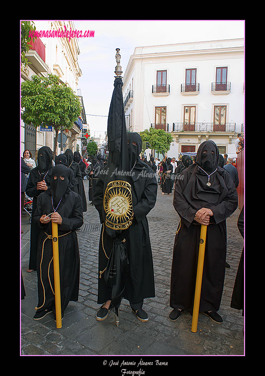 Nazareno portando la Bandera de la Compañía de Jesús de la Hermandad de Nuestra Señora de Amor y Sacrificio