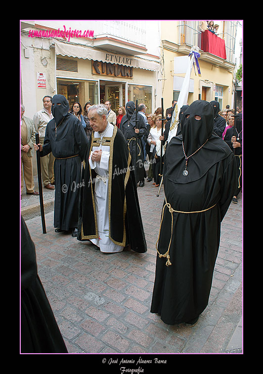 Preste con acólitos tras el Paso de Nuestra Señora de Amor y Sacrificio