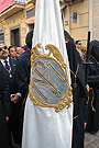 Nazareno portando la Bandera de Devotos de la Hermandad de Nuestra Señora de Amor y Sacrificio