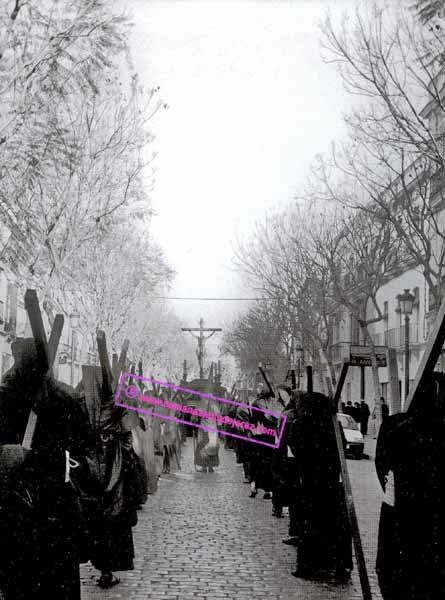 Mañana del Viernes Santo, el Santísimo Cristo de la Buena Muerte por calle Porvera camino de su sede, la Parroquia de Santiago. En la foto puede verse el recogimiento de los nazarenos y penitentes, final de los años 80 (Foto: Diego Romero)