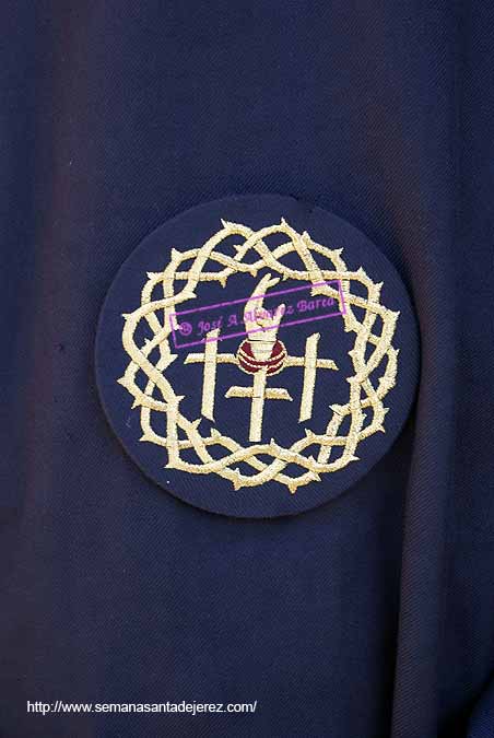 Escudo de la Hermandad sobre el antifaz de los nazarenos de la Hermandad del Santísimo Cristo del Perdón