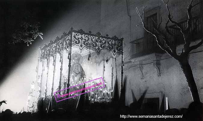 El Paso de Nuestra Madre y Señora de la Soledad (año 1966) iluminado por los reflectores de luces que colocaba el Regimiento de Artilleria 74 por aquellos años en la calle Por-vera. Por entonces la cofradia solo hacia estación con un solo paso y salía y entraba a su templo por la puerta principal de la Iglesia de la Victoria (Foto: Eduardo Pereiras Hurtado, año 1966).