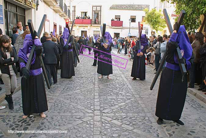 Penitentes con cruces tras el paso de Misterio de la Hermandad de la Soledad 