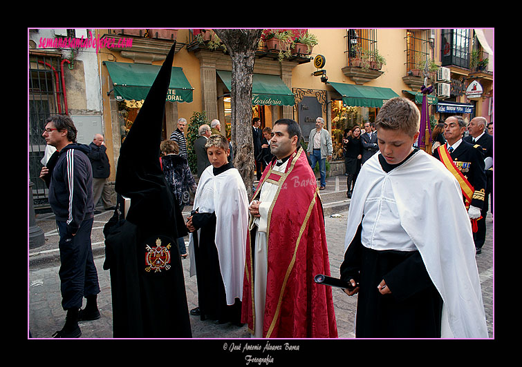 Nazareno portando el Libro de Difuntos y Preste acompañado de acólitos, tras la Urna en la Hermandad del Santo Entierro