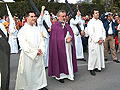 Preste acompañado de acolitos tras el Paso de Misterio de la Hermandad de la Clemencia