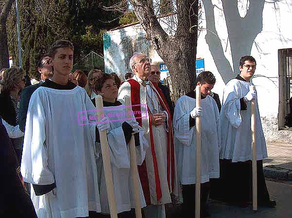 Preste con acólitos tras el Paso de Misterio de la Hermandad de la Redención